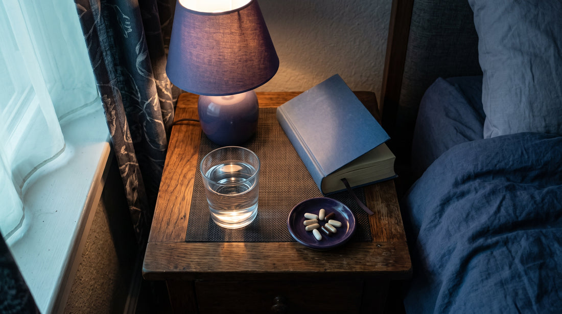 Comodino con integratori per dormire, bicchiere d'acqua e luce soffusa serale